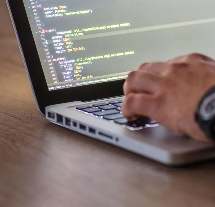 Χέρι πληκτρολογεί κώδικα σε laptop κατά την ανάπτυξη ιστοσελίδας